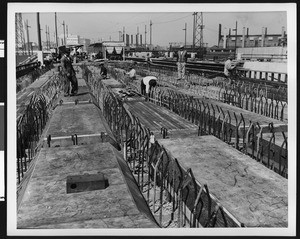 Men standing on grid layout of a factory, ca.1940