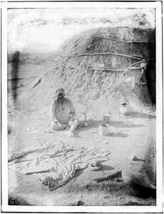 Pima Indian man, Ho-Dutch, sitting in front of his native dwelling, or "Kan", Pima, Arizona, ca.1900