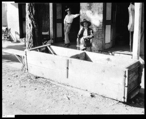 Hubert Brady and an unknown man situated behind a large horse trough at the "Stage Driver's Retreat", ca.1930