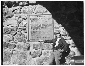 A woman standing by a plaque on a wall in Big Pines Camp