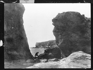 Man standing between rock formations on Shell Beach, El Pismo, ca.1905