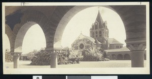 Exterior view of Memorial Church from underneath an arcade or corridor at Stanford University, ca.1900