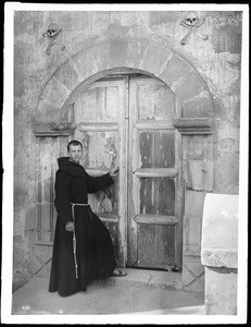 Mission Santa Barbara, showing priest standing at door from church to cemetery, California, 1898