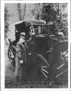 Portrait of stagecoach driver, Henry Hodges, standing beside his old stagecoach, ca.1874-1890