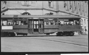 Trolley car passing along a large building, ca.1930