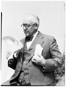 Man holding what appears to be pieces of bone at the Pacific Southwest Museum