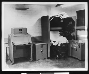 Man working at an elaborate electronic desk inside an electronics plant, ca.1940