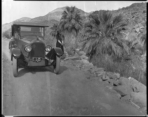 View of a rocky landscape, showing a woman and an automobile, ca.1920