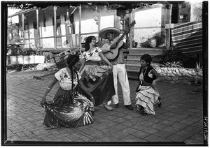 Several performers posing before the Avila adobe on Olvera Street