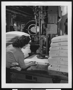 Woman marking numbers on white rubber pads, ca.1950