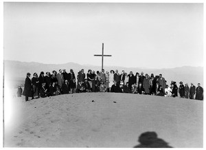 Group of people posed in front of a cross at a funeral in the desert