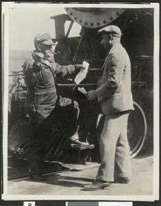 Penzoil Company's James V. Leonett examining the train orders of locomotive engineer S.C. Mason of Southern Pacific Railroad, ca.1920