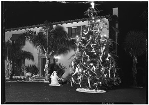 Outdoor Christmas tree outside of home, showing snowman on front lawn, December 26, 1930