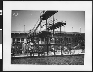 Swimmer leaping off a diving tower in Exposition Park in front of the Los Angeles Memorial Coliseum, ca.1932