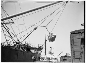 Ship loading a parcel of sacks at an unidentified harbor