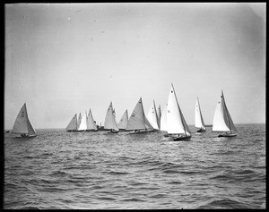 Several sailboats grouped tightly together in the middle of an unidentified body of water