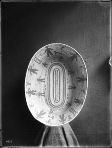 Indian basket displayed in front of a cloth backdrop, ca.1900