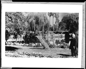 View of E.J. "Lucky" Baldwin standing by a lake at his estate, ca.1900