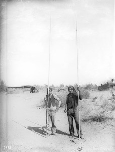 Two young Yuma Indian men with implements for the pole and hoop game