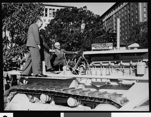 Three men on a bulldozer during the groundbreaking ceremony for Pershing Square parking garage, 1951