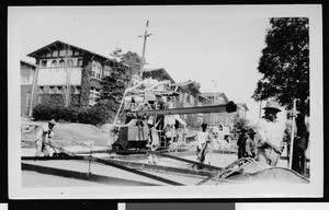 Workers using a Rex 27-E paver smoothing concrete on a street with hand floats