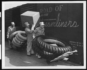 Three workers unloading tires from a rail car, ca.1950