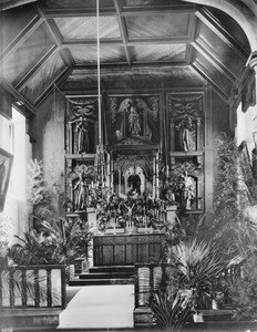 Interior view of the Mission San Gabriel showing the altar lavishly decorated for a wedding, ca.1895