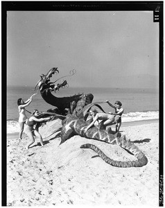 Women subduing a fake dragon on the sand of a Los Angeles area beach, ca.1940