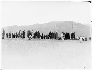 Men and women congregating around a cross at a funeral