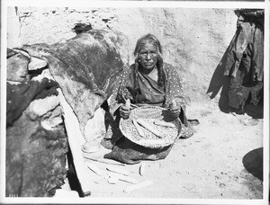 Hopi Indian woman shelling corn from the cob, ca.1900