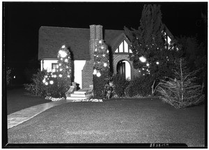 Outdoor Christmas decorations on single story house, showing lights on bushes, December 26, 1930