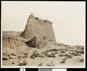 View of Red Rock Canyon with two men standing on top of a rock formation, Death Valley, California, ca.1900/1950