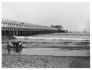 Long Beach Pier and Pavilion showing children digging in the sand, ca.1905