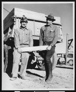 Cecil and Clifford Burton holding a large gold and silver bar from the Tropico Hill ore, ca.1930