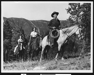 A group of people horseback riding in a mountainous area, ca.1940