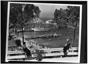 Two women seated on a fence overlooking Avalon Harbor on Catalina Island