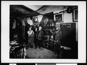 Three Sunset Club members in costume posing in front of a fireplace, ca.1910