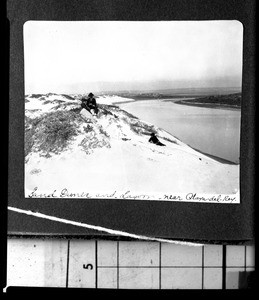 Family sitting on a sand dune near a lagoon in Playa del Rey, ca.1902