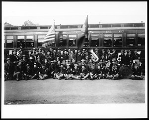 Portrait of veterans "Teddy's Terrors" in front of a Santa Fe train with their band, ca.1904