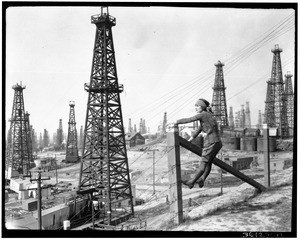 Woman Standing on a Wire Fence Above an Oil Field