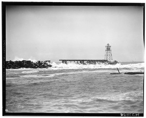 Weather beaten Long Beach breakwater partially damaged with parts of it floating in the water at right