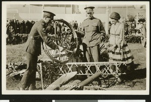 Three people examining a zeppelin wreckage at the World War I Allied War Exposition in Los Angeles, August 1-10, 1918