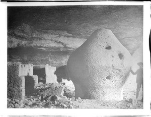 Man standing next to a granary of the Indian cliff dwellings, Sierra Madre, Mexico, ca.1900