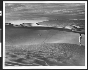 Woman standing beside an expanse of dunes, ca.1940