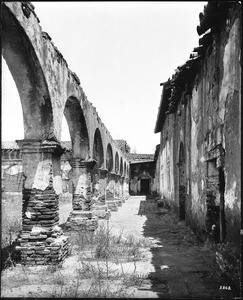 View of the corridor at Mission San Juan Capistrano, as seen from the west side of the mission, Orange County, California, 1885