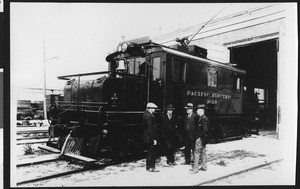 Men standing beside a Pacific Electric railway car in Torrance Shops, 1924