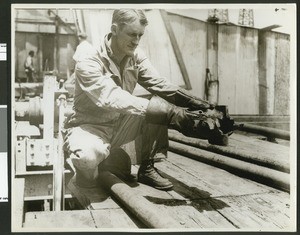 Chief driller K.M. East inspecting a drill bit, ca.1940