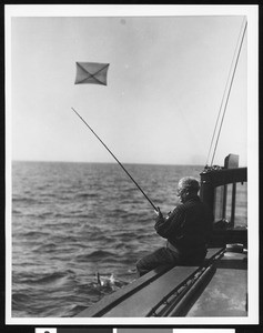 A man fishing with a kite on a boat, ca.1930