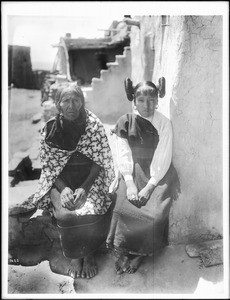 Hopi Indian mother and daughter sitting outside, ca.1900