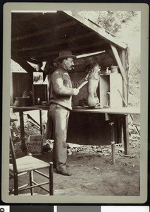 A fishing club member preparing to carve a pig, ca.1910-1920